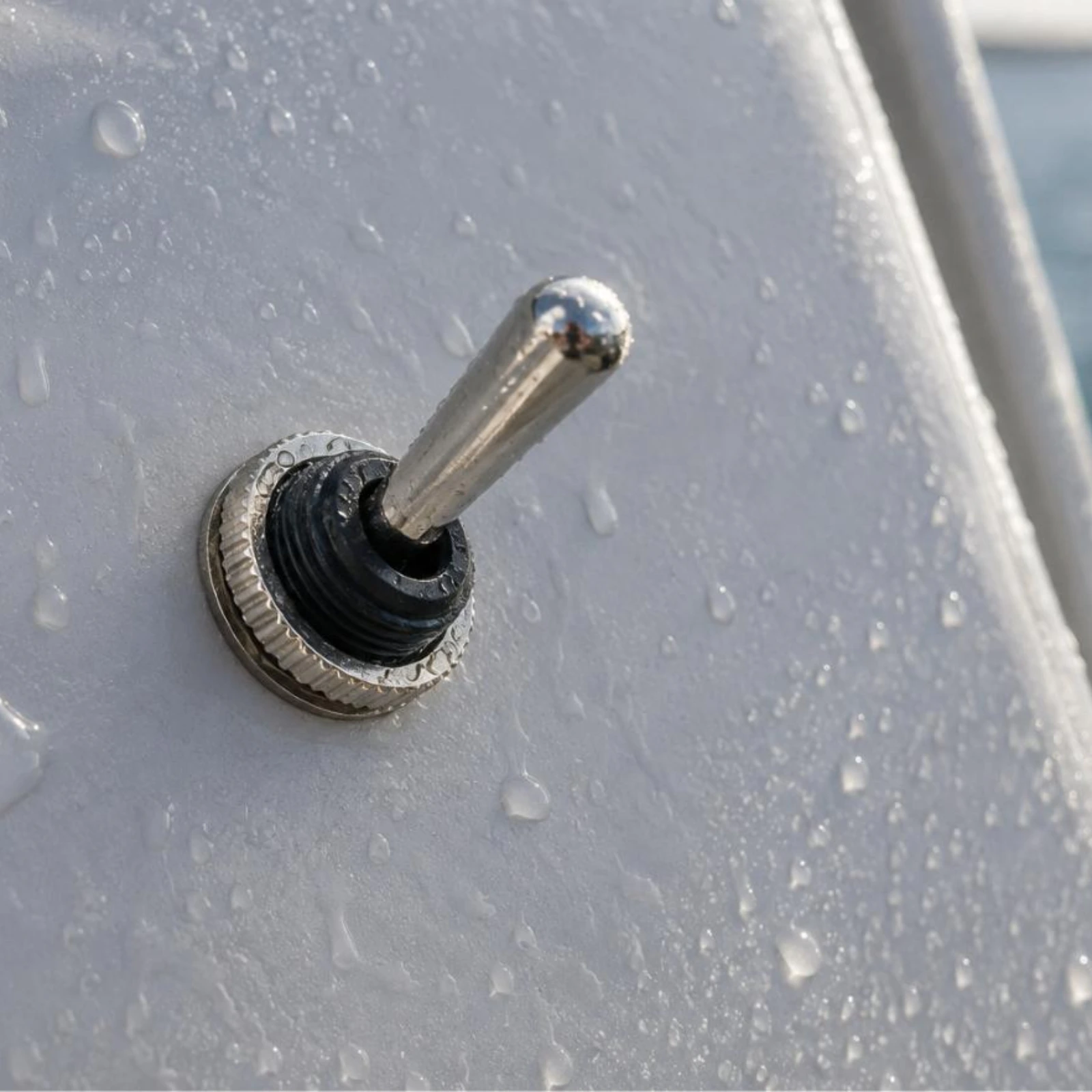 Marine toggle switch installed on boat panel, metal parts visible, water spray