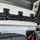 Black cable tie mounts screwed to a canopy panel with cable ties holding a wiring loom