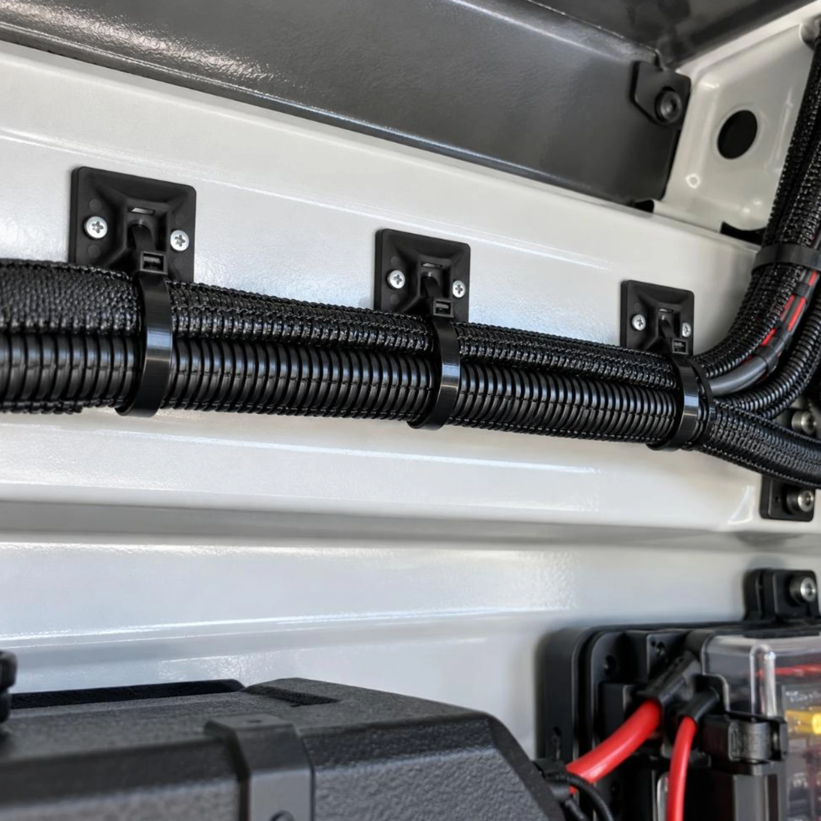 Black cable tie mounts screwed to a canopy panel with cable ties holding a wiring loom
