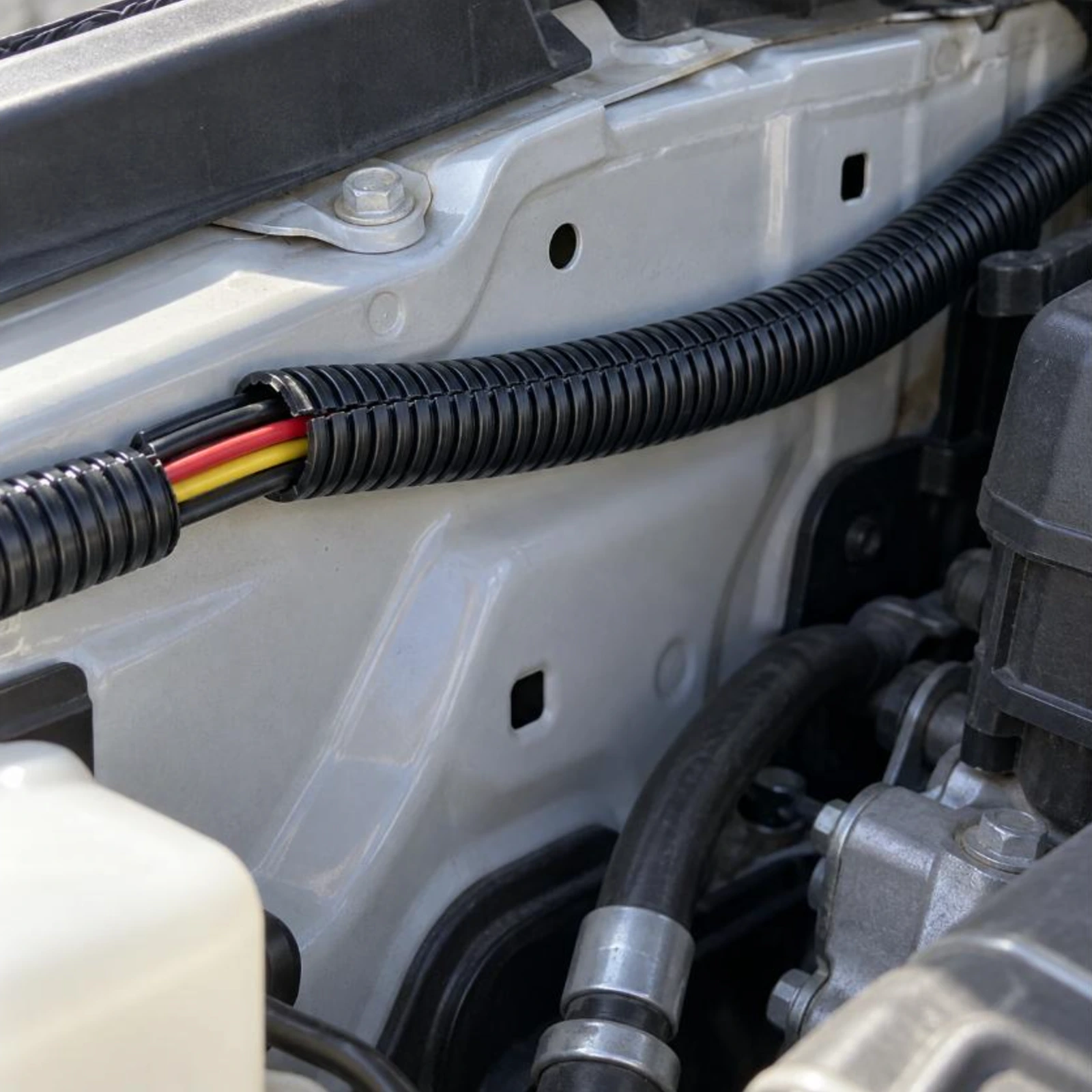 Black split convoluted tubing protecting a wiring loom in an engine bay